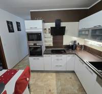 A kitchen in a 3-room apartment with light fixtures, white cabinets, and tiles.