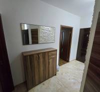 Hallway in a 3-room apartment with a tiled floor and a mirror above the cabinet.