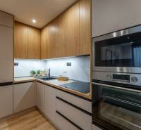 A kitchen in a 2-room apartment with a wood-patterned floor, wooden cabinets, and appliances.
