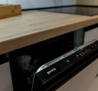 In the kitchen of the two-room apartment, there is a Gorenje dishwasher and a floor with a wood decor.