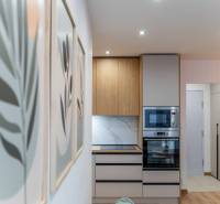 A kitchen in a 2-room apartment with an oven, microwave, and a floor with a wooden decor.