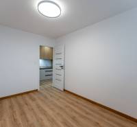 A room with a wooden floor decor, the door leads to the kitchen in a 2-room apartment.