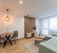 Living room in a two-room apartment with a wooden decor floor, a comfortable sofa, and a table.