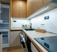 Kitchen in a 2-room apartment with wood-patterned flooring, built-in appliances, white tiles.