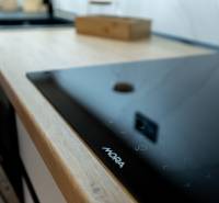 Detail of the kitchen countertop and cooktop in a two-room apartment with a wooden decor floor.