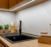 The kitchen area of a 2-room apartment with wooden accessories and plants on the countertop.