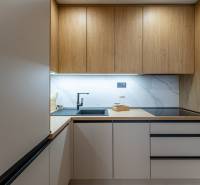 A kitchen with a wood-patterned floor and built-in appliances in a two-room apartment.