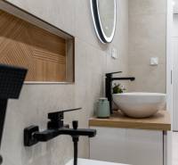 Bathroom in a 2-room apartment with a modern sink and illuminated mirror.