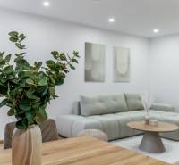Living area of a 3-room apartment with a sofa, table, and flowers in light shades.
