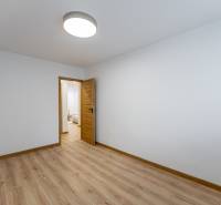 White room with wood-patterned flooring and doors in a three-room apartment.