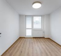 A room in a 3-room apartment with a wooden decor floor and a large window.