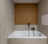 A bathroom with a bathtub and a wall with a wooden decor in a 3-room apartment.