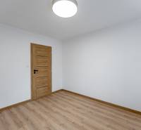 A room with a wooden decor floor and wooden doors in a 3-room apartment.