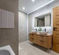 Bathroom in a 3-room apartment with sinks, wooden doors, and a lighted mirror.