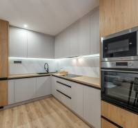 A kitchen in a 3-room apartment with a wooden decor floor and modern appliances.