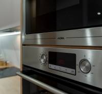 A kitchen unit in a 3-room apartment with a stainless steel oven and microwave.