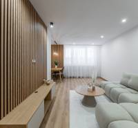 Living room with wooden decor, light sofa, and dining area in a three-room apartment.