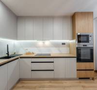 A kitchen unit with light cabinets, a floor with a wooden decor, a 3-room apartment.