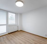 A room in a 3-room apartment with a large window, a radiator, and a floor with a wood decor.