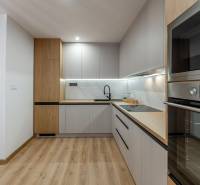 A kitchen in a 3-room apartment with a wood-patterned floor, light cabinets, and a built-in oven.