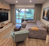Living room in a family house with a wooden decor floor, corner sofa, and television.