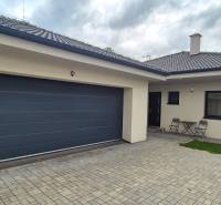 A family house in Studienka with two chairs and a table on a paved courtyard.