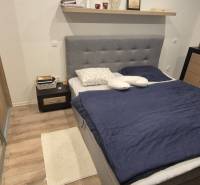 Bedroom with wood-patterned flooring, bed, and storage spaces in a family house.