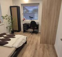 Bedroom with a bed, table, and wooden decor flooring in a family house.