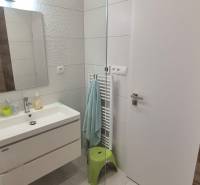 Bathroom in a family house with a sink, embossed tiles, mirror, and illuminated walls.