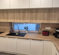 A kitchen in a family house with white cabinets and a wooden decor countertop.