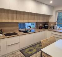 A kitchen in a family house with white cabinets, appliances, and a wooden decor floor.