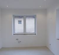 Empty room with white walls and a large window in a family house.