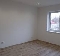 A room in a family house with white walls and a wooden decor floor.