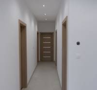 A hallway in a family house with white walls and wooden decor doors.