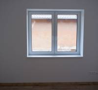 A room in a family house with a large window and a floor with a wooden decor.