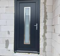 The entrance door of a family house in Radava, surrounded by brick masonry.