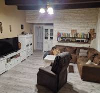 Living room with a corner sofa, white furniture, and a wooden decor floor in a family house.