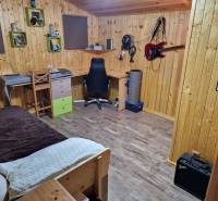 A room with wooden walls, a floor with a wooden decor, a desk, and a guitar on the wall.