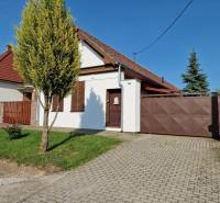 A family house in Dlhá nad Váhom with a gate and a front garden, complemented by trees.