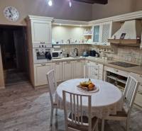 A kitchen in a family house with a wooden decor floor, tiles, and a round table.