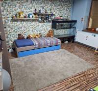 Children's room with a bed, aquarium, toys, and a floor with a wooden decor in a family house.