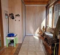 Hallway with tiles, built-in wardrobe, and bench in a family house.