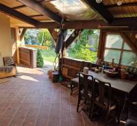 Rustic terrace of a family house with wooden furniture and a view of the garden.