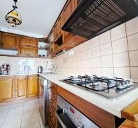 A kitchen in a family house with a gas stove, dark brown cabinets, and ceramic tiles.