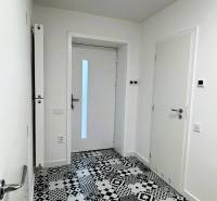 A hallway in a family house with tiled flooring and patterned decor, white walls, doors.