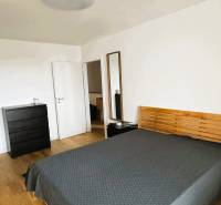 Bedroom in a family house with a bed, dresser, and wooden decor flooring.