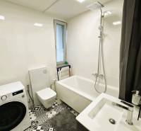 A bathroom in a family house with a bathtub, washing machine, and black-and-white floor with a geometric pattern.