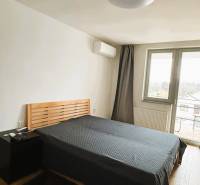 Bedroom with a bed, nightstand, and wood-patterned flooring in a family house.