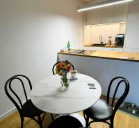 Dining room in a family house with a round table, flowers, and a wooden-patterned floor.