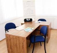 Office with a wooden desk, blue chairs, and a board, commercial premises.